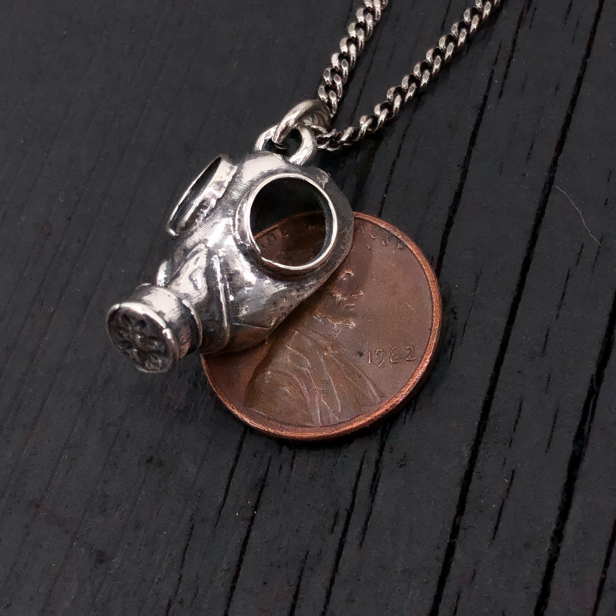 This classic World War 2 era gas mask is scaled down to a mere 3/4" long by 9/16" wide. It is cast in solid sterling silver with a textured oxidized finish that gives it a wonderful post apocalyptic appearance.