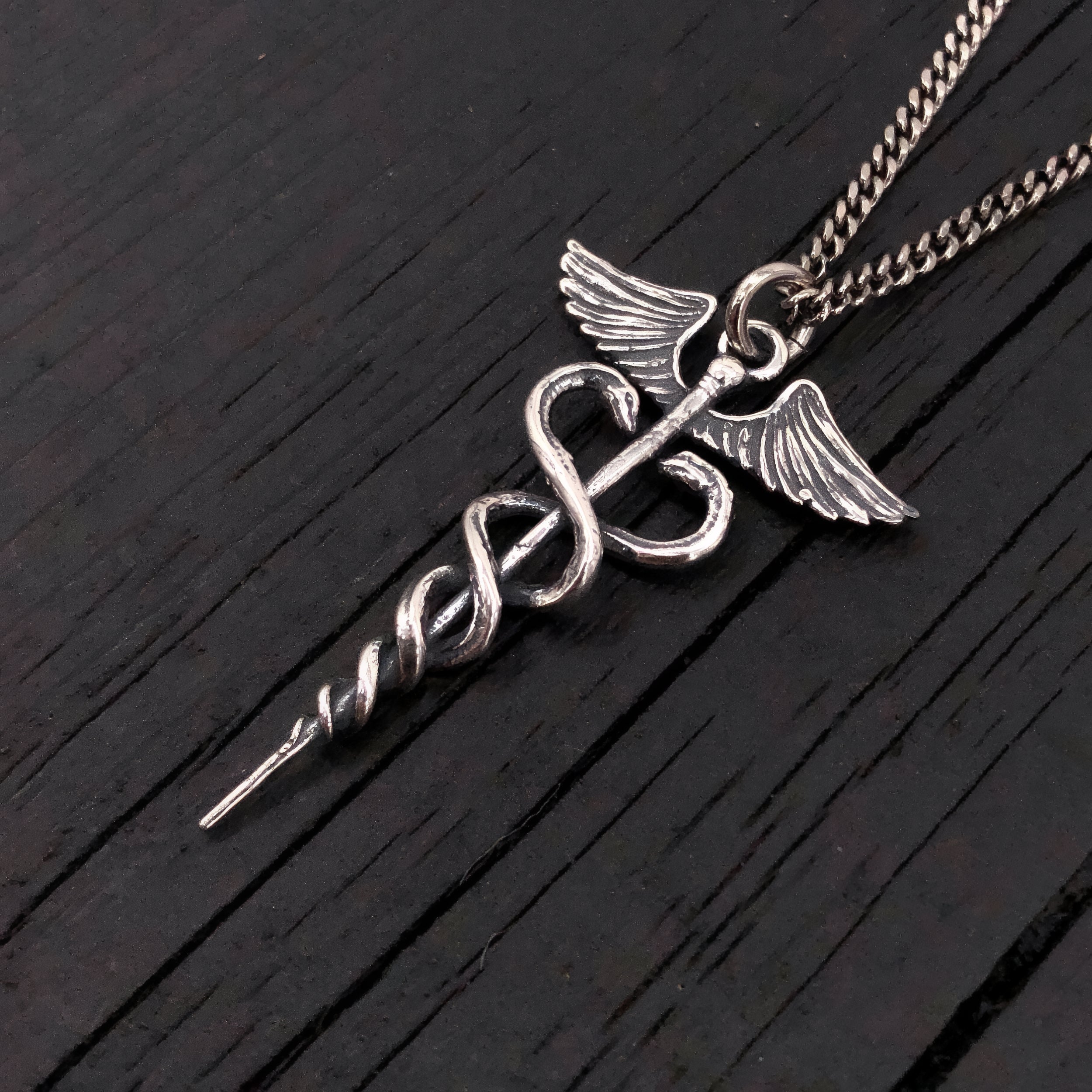 This beautifully detailed caduceus is cast in sterling silver, oxidized in recesses to enhance the fines detail of this 1.5" long pendant.