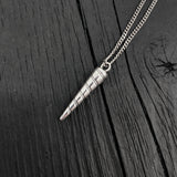 Silver cone-shaped pendant on a chain against a dark wooden background