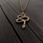 Snake pendant on wooden table, intricate design | Moon Raven